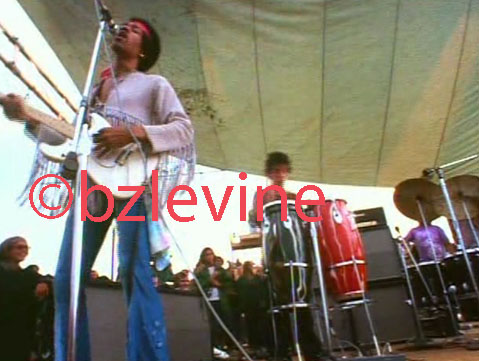 Jimi Hendrix Band of Gypsies performing monday morning at Woodstock as featured (p26-27) in the Jimi Hendrix Live at Woodstock Alblum's 12x12 36 page Promotional book commemorating the 35Th Anniversary of Jimi's performance at the Woodstock Festival